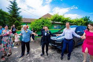 A festive outdoor celebration with people joined in a traditional dance line against a blue sky.