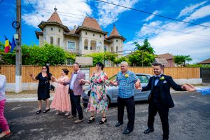 People performing a traditional line dance outdoors with historic architecture visible behind them.