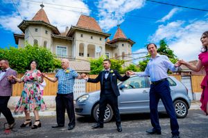 People engaged in a coordinated dance routine on a paved road with European-style buildings nearby.