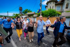 Street dancers performing choreographed moves during a community celebration under blue skies.