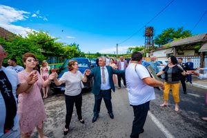 Community members participating in a synchronized street dance with buildings and trees in background.