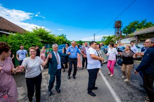 Wide panoramic view of people dancing in formation during an outdoor community event.