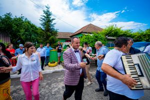 People dancing in a coordinated line formation during a sunny outdoor gathering.