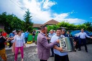 A group dancing together at an outdoor celebration with an accordion player.