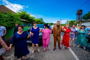 Festive outdoor celebration with people dancing in traditional style on a sunny afternoon.