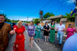 Colorfully dressed dancers holding hands in a line during an outdoor celebration.