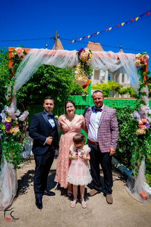 Decorated outdoor venue with white fabric draping and floral arrangements for a celebration.