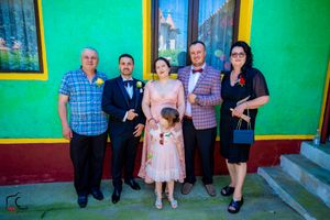 Group portrait taken outside a building with distinctive green walls and yellow window frames.