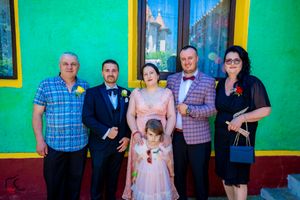 Family gathering posed in front of a colorful building with green walls and yellow accents.