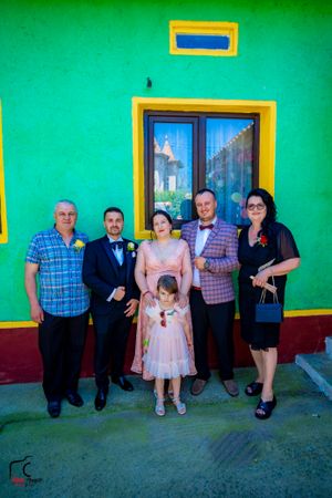 Casual group photo of people standing in front of a vivid green building with yellow trim.
