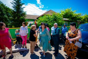 People socializing at an outdoor gathering with lush green landscaping in the background.