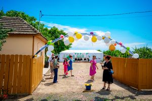 Outdoor wedding venue with white tents and colorful bunting decorations against a bright blue sky.