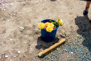 Scattered flower petals and decorative elements on a sandy ground at an outdoor event.