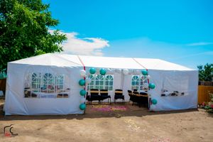 Row of large white wedding tents set up on a sunny day with blue skies.