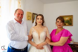 Wedding preparation scene with bride and family members in a white-walled room with framed artwork.