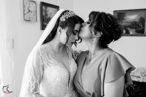 A tender moment shared between a bride in a lace gown and someone wearing bright pink in an elegantly decorated room.