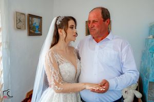 A tender moment captured between a bride in a detailed lace gown and companion in a white dress shirt.