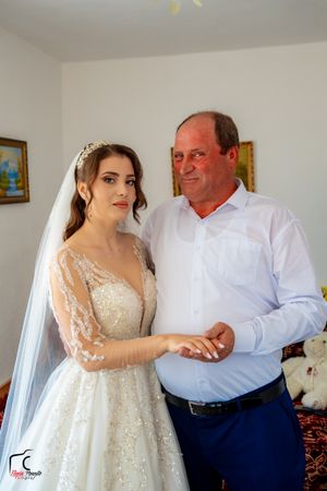 A wedding day portrait showing a bride in a sparkly gown with a companion in casual formal attire.