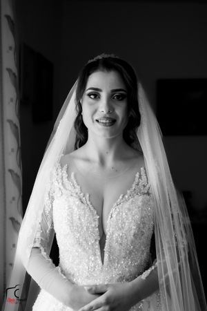 Black and white portrait of a bride in a beaded wedding gown with plunging neckline and long veil.