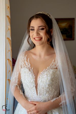 Radiant bridal portrait showcasing intricate beadwork on wedding dress with matching tiara and veil.