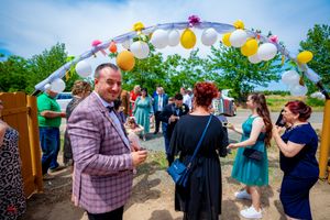 Festive outdoor gathering with yellow and purple balloon decorations under blue skies.