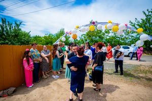 Panoramic view of outdoor wedding celebration with balloon arch and gathered guests.