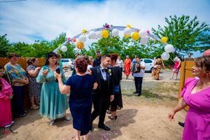 Guests gathered for outdoor wedding festivities under balloon-decorated archway.