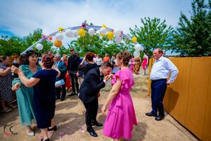 Panoramic view of wedding celebration with decorated arch and mingling guests.