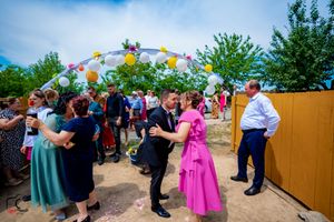 Wedding guests celebrating under colorful balloon arch at outdoor venue.