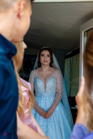 A sparkling light blue wedding gown with delicate lace details is showcased indoors.
