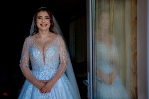 An elegant light blue wedding dress with intricate beading and long sleeves is displayed.
