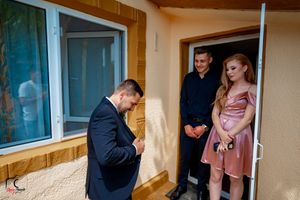 First look wedding moment captured in doorway of cream colored building with blue trim.