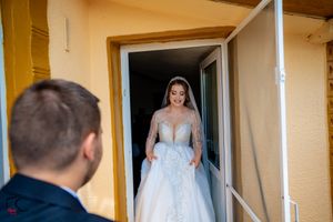 Bride and groom having their first look meeting outside rustic venue with wooden beams.