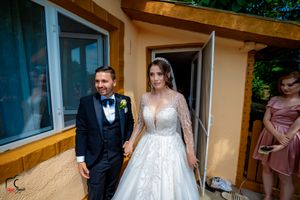 Wedding party and guests mingling outside venue under bright blue sky.