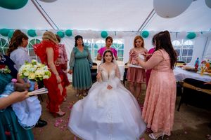 Wedding reception under white tent with teal accents and colorfully dressed guests.