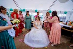Wedding celebration inside tent with festive decorations and guests in colorful attire.