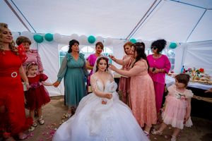 Wedding party gathering under decorated white tent with teal and white balloon decor.