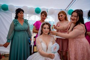 Wedding celebration with attendees in colorful dresses under white tent with teal decorations.