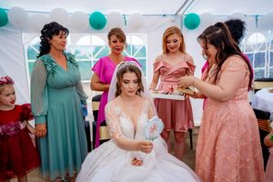 Wedding celebration showing attendees in formal attire with teal balloon decorations in the background.
