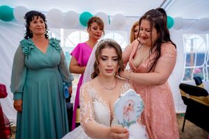Formal wedding reception showing guests in coordinated dresses under tent with teal decorations.