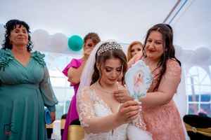 Wedding party members celebrate in formal attire under white tent with teal balloon accents.