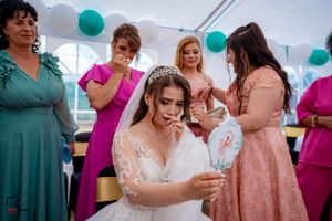 Wedding celebration with attendees in coordinated formal wear under decorated white tent.