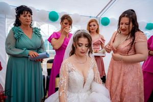 Wedding party members in teal and pink dresses gather together during an outdoor reception celebration.