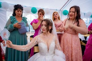 Guests in vibrant formal attire celebrate at a wedding reception under a tent with teal balloon decor.