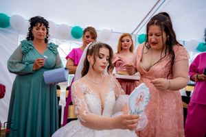 Wedding guests in jewel-toned dresses gather for festivities under a white tent with teal accents.