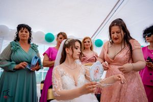 Wedding reception scene with guests in coordinated teal and pink dresses celebrating under a tent.