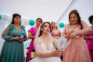 Wedding celebration featuring guests in coordinated formal wear gathered under a white tent with balloons.