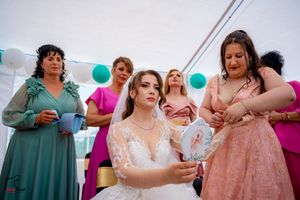 Wedding party members in teal and pink dresses socialize during an outdoor tented reception.