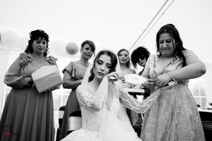Wedding party guests in colorful dresses gather under a white tent for celebration.