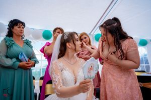 Bridal party members in coordinated dresses share conversation at tented reception.